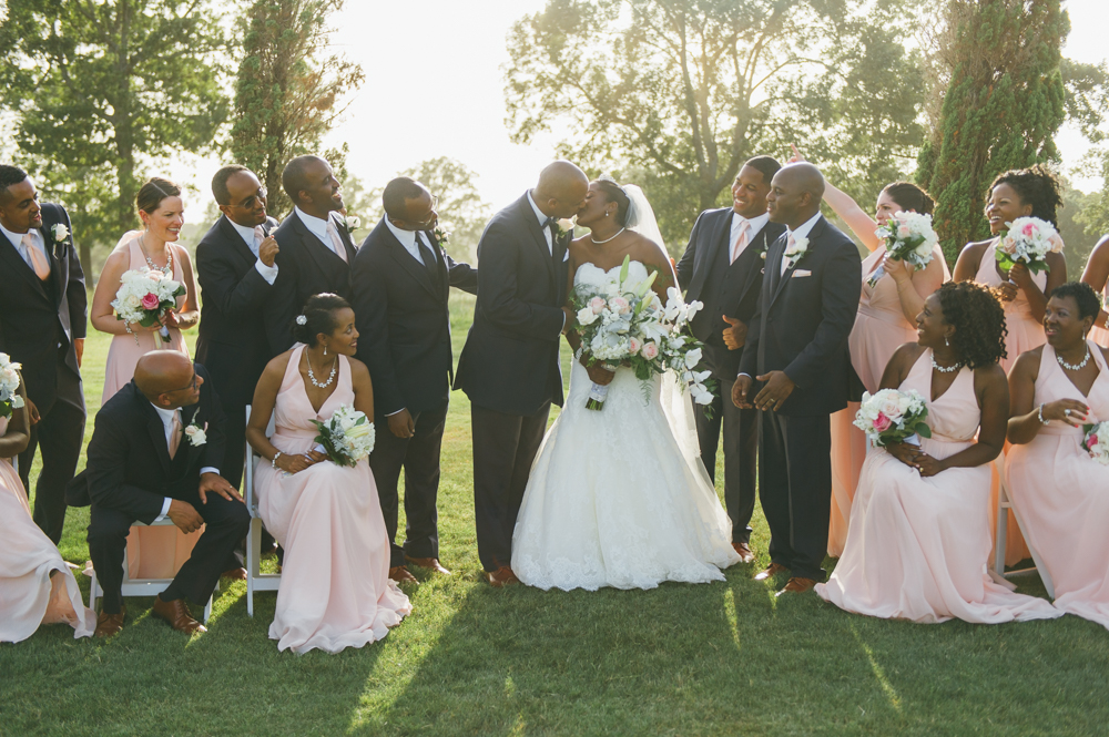 Bride and groom kiss standing on a grassy field. The bridal party is seated and standing on either side of them.

Luxury Texas Wedding Photographer. Timeless Wedding Photography. Wedding in Texas. Destination Wedding Photographer.