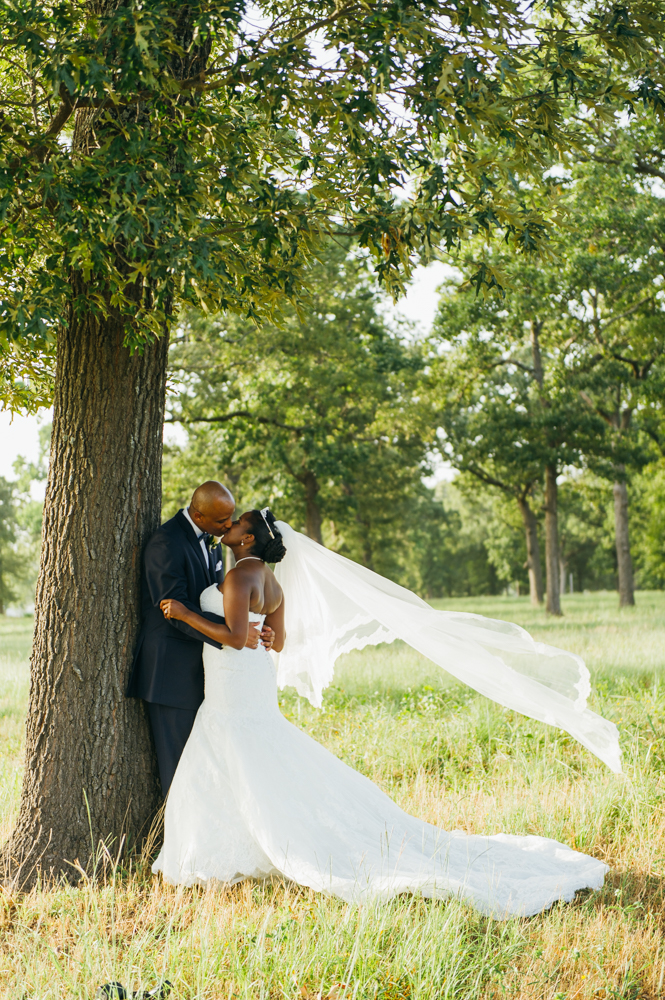 Groom stands with his back against a tree. Bride stands facing him. They have their arms around each other and kiss as he veil blows in the wind.

Luxury Texas Wedding Photographer. Timeless Wedding Photography. Wedding in Texas. Destination Wedding Photographer.