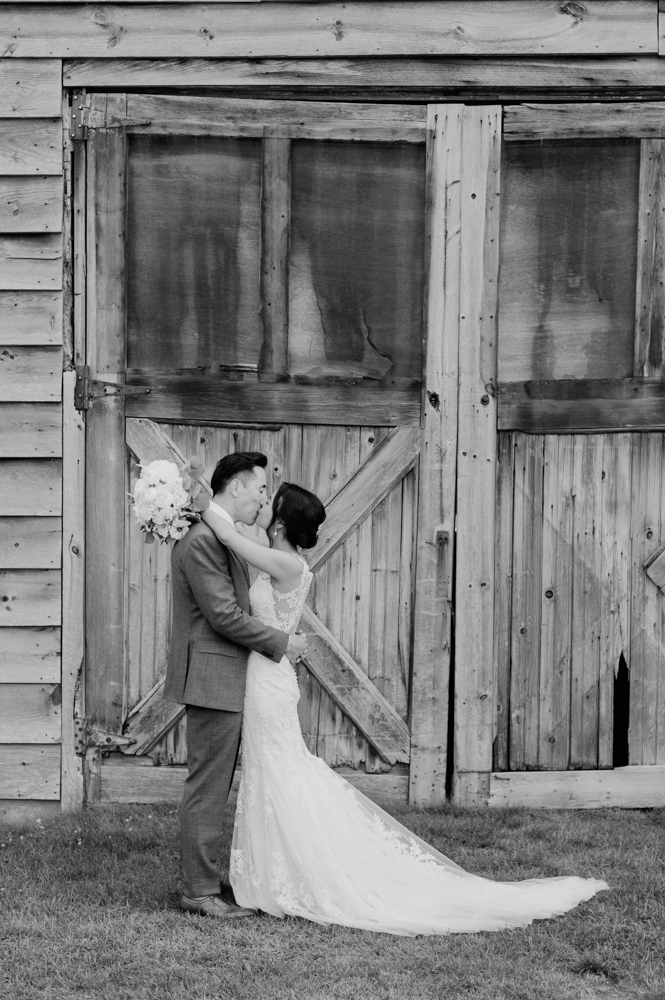 Bride and groom kiss outside a barn with their arms around each other.

Highlands Country Club Wedding. Upstate NY Wedding Photographer. Luxury Wedding Photographer. Upstate New York Wedding Photography.
