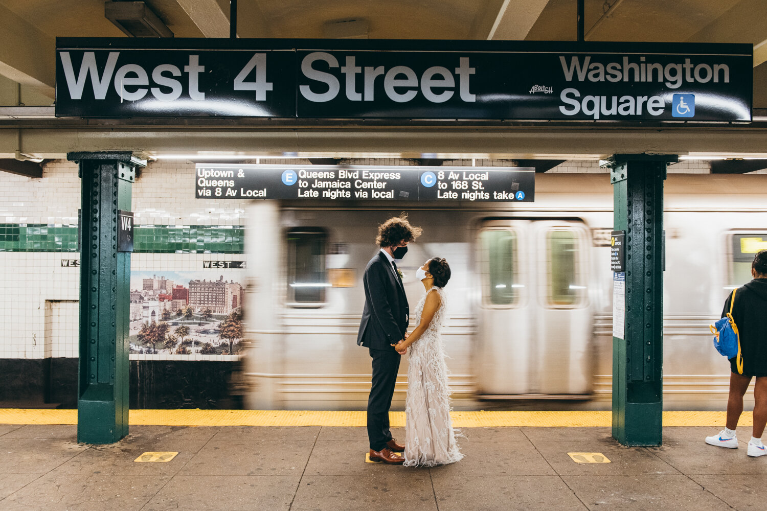 Bride and groom stand facing each other, holding hands, and looking into each other's eyes with masks on in the subway station. The subway is moving behind them and they are below a sign that says "West 4th Street"

Central Park Wedding Photography. Williamsburg Bridge Bridal Portraits. Luxury NYC Wedding Photographer. Manhattan Micro Wedding.