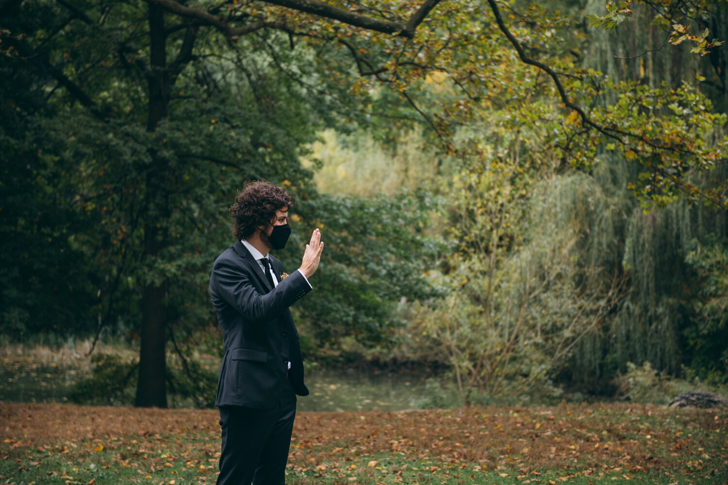 Groom stands in Central Park with trees behind him. He is wearing a mask and holding his hand up in a wave looking off camera.

Central Park Wedding Photography. Williamsburg Bridge Bridal Portraits. Luxury NYC Wedding Photographer. Manhattan Micro Wedding.