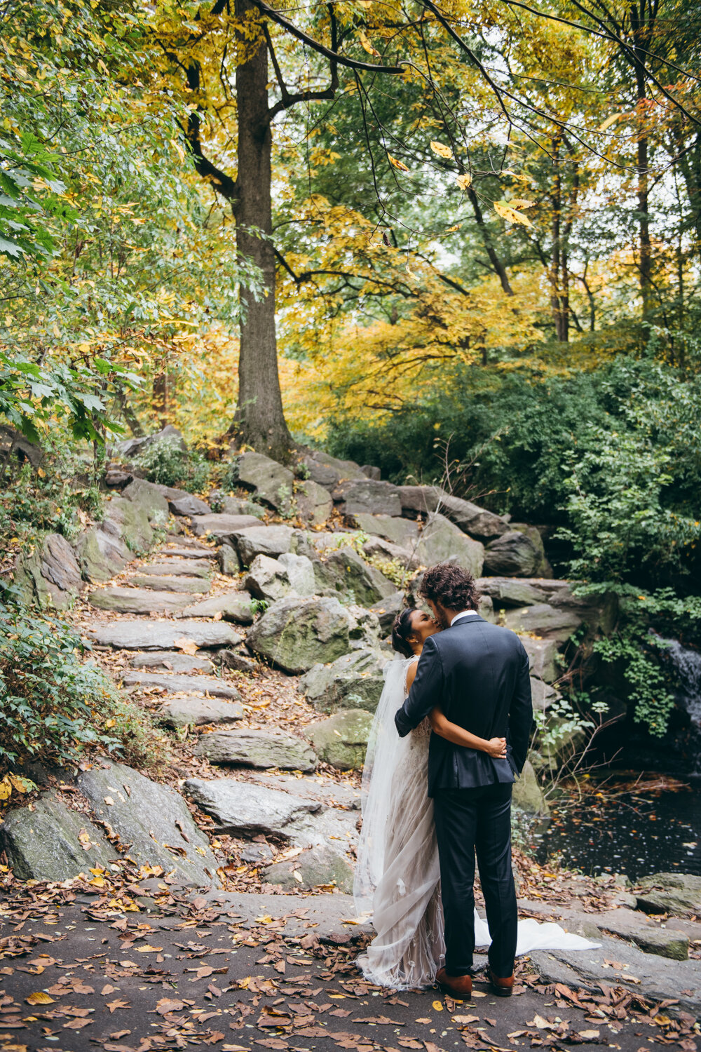 Bride and groom have their arms around each other and kiss in Central Park in front of a path of rocks and trees.

Central Park Wedding Photography. Williamsburg Bridge Bridal Portraits. Luxury NYC Wedding Photographer. Manhattan Micro Wedding.
