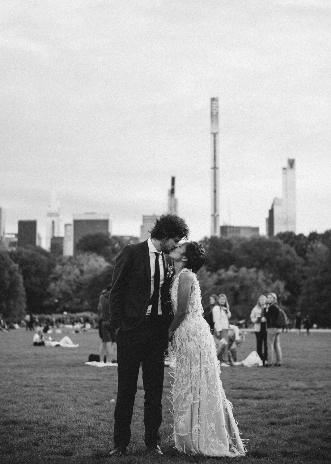 Bride and groom kiss standing on the grass in Central Park. Trees, Manhattan buildings, and park-goers are visible in the background.

Central Park Wedding Photography. Williamsburg Bridge Bridal Portraits. Luxury NYC Wedding Photographer. Manhattan Micro Wedding.