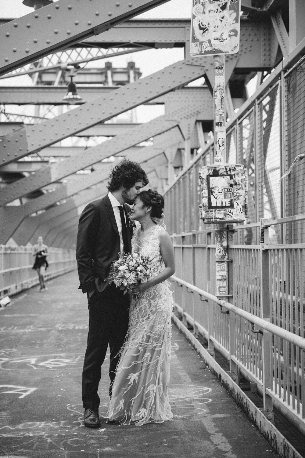 Bride and groom stand together on the Williamsburg Bridge. She is holding a bouquet of flowers and smiling and he is kissing her forehead.

Central Park Wedding Photography. Williamsburg Bridge Bridal Portraits. Luxury NYC Wedding Photographer. Manhattan Micro Wedding.