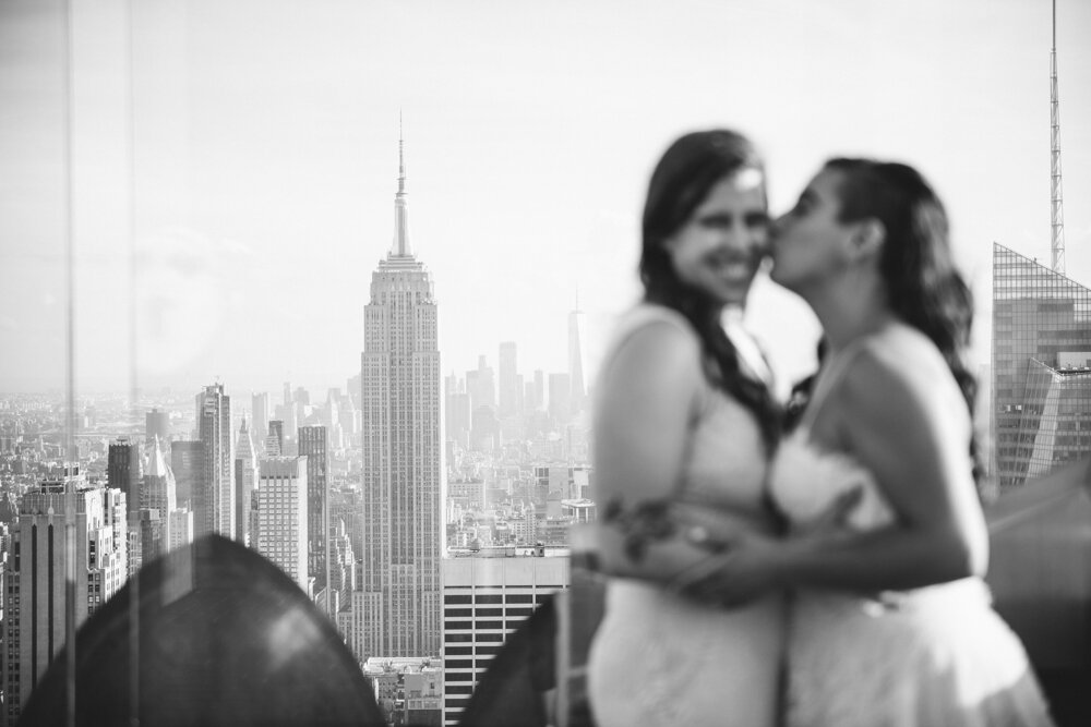 One bride kisses the other on the cheek out of focus in the foreground. In the background in focus is the Empire State Building and the Manhattan skyline.

Luxury NYC Wedding Photography. Queer Wedding Photography. Inclusive Wedding Photographer. LGBTQ+ Manhattan Wedding.