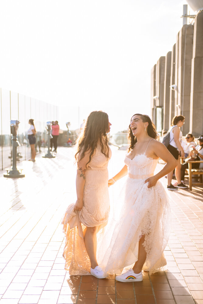 Two brides stand at the Top of the Rock and smile whole holding up their dress skirts to reveal white sneakers.

Luxury NYC Wedding Photography. Queer Wedding Photography. Inclusive Wedding Photographer. LGBTQ+ Manhattan Wedding.