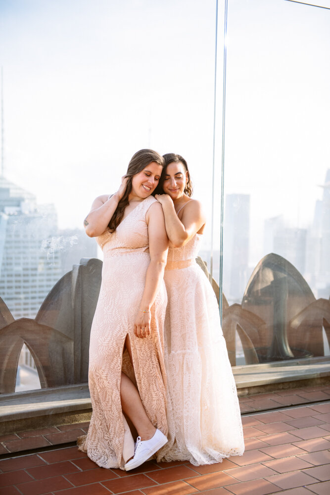 One bride stands behind the other with her hand on her shoulder. They are both smiling and looking to the ground with the Manhattan skyline behind them.

Luxury NYC Wedding Photography. Queer Wedding Photography. Inclusive Wedding Photographer. LGBTQ+ Manhattan Wedding.