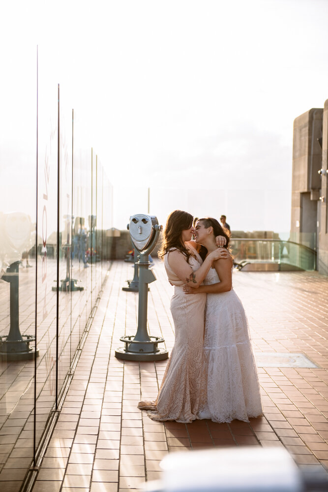 Two brides kiss at the Top of the Rock with their arms around each other.

Luxury NYC Wedding Photography. Queer Wedding Photography. Inclusive Wedding Photographer. LGBTQ+ Manhattan Wedding.