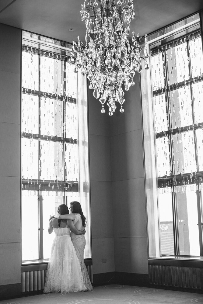 Two brides stand with arms around each other in a ballroom at Rockefeller Center. They are standing in front of tall windows below a large crystal chandelier.

Luxury NYC Wedding Photography. Queer Wedding Photography. Inclusive Wedding Photographer. LGBTQ+ Manhattan Wedding.