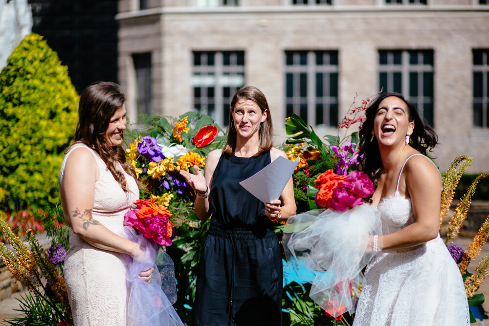 Two brides laugh and smile at the altar as the wedding officiant reads from a paper. They are at Top of the Rock.

Luxury NYC Wedding Photography. Queer Wedding Photography. Inclusive Wedding Photographer. LGBTQ+ Manhattan Wedding.