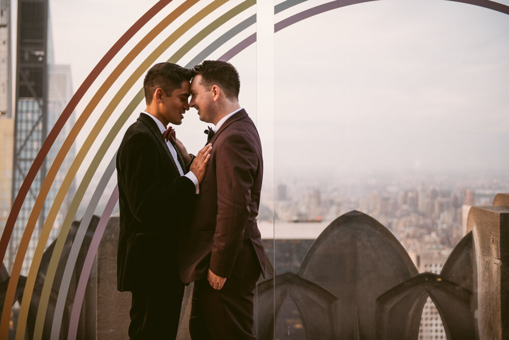 Grooms stand facing each other with foreheads and noses touching. One groom has his hands on the other's chest. The Manhattan skyline is visible behind them.

Luxury NYC Wedding Photography. Queer Wedding Photography. Inclusive Wedding Photographer. LGBTQ+ Manhattan Wedding.