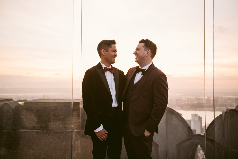 Two grooms stand next to each other at the Top of the Rock and smile at each other. The Manhattan skyline is visible behind them.

Luxury NYC Wedding Photography. Queer Wedding Photography. Inclusive Wedding Photographer. LGBTQ+ Manhattan Wedding.
