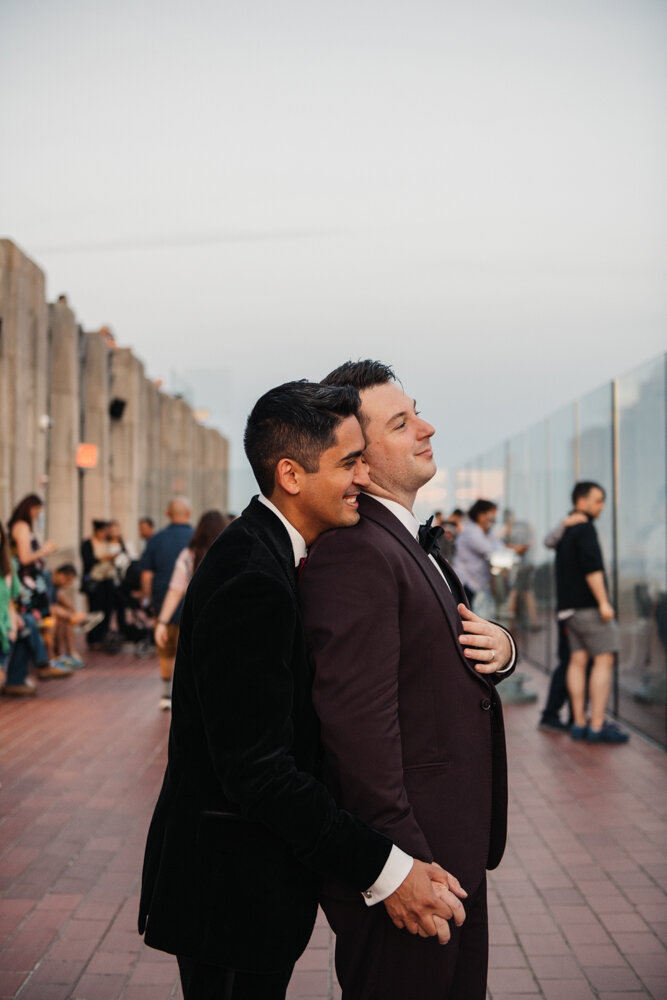 One groom stand behind the other with his head resting on his shoulder. They are both smiling and holding hands.

Luxury NYC Wedding Photography. Queer Wedding Photography. Inclusive Wedding Photographer. LGBTQ+ Manhattan Wedding.