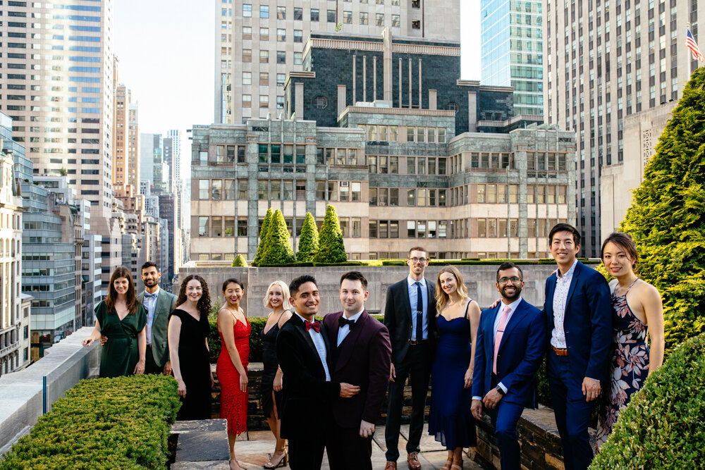 Grooms pose with arms around each other. They are surrounded by wedding guests all smiling at the camera. The Manhattan skyline is visible behind them.

Luxury NYC Wedding Photography. Queer Wedding Photography. Inclusive Wedding Photographer. LGBTQ+ Manhattan Wedding.