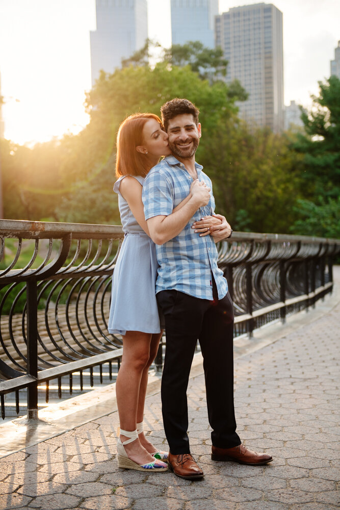 Woman stands behind man with her arms around him and kissing him on the cheek. He smiles at the camera with Central Park and the Manhattan skyline behind them.

Central Park Engagement Portraits. Manhattan Engagement Photography. NYC Engagement Photographer.