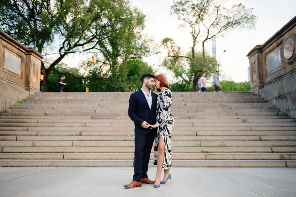 Man and woman stand facing each other with their foreheads touching. They are holding hands standing at the bottom of steps in Central Park in Manhattan.

Central Park Engagement Portraits. Manhattan Engagement Photography. NYC Engagement Photographer.