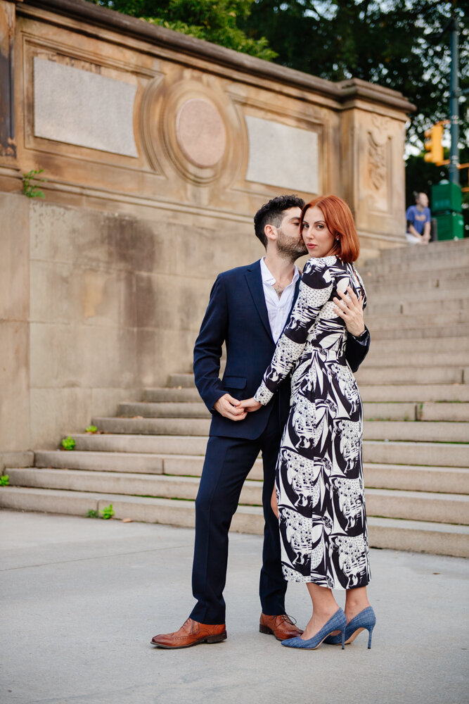 Man kisses woman on the cheek as she looks into the camera. They are holding hands and standing at the bottom of steps in Central Park.

Central Park Engagement Portraits. Manhattan Engagement Photography. NYC Engagement Photographer.