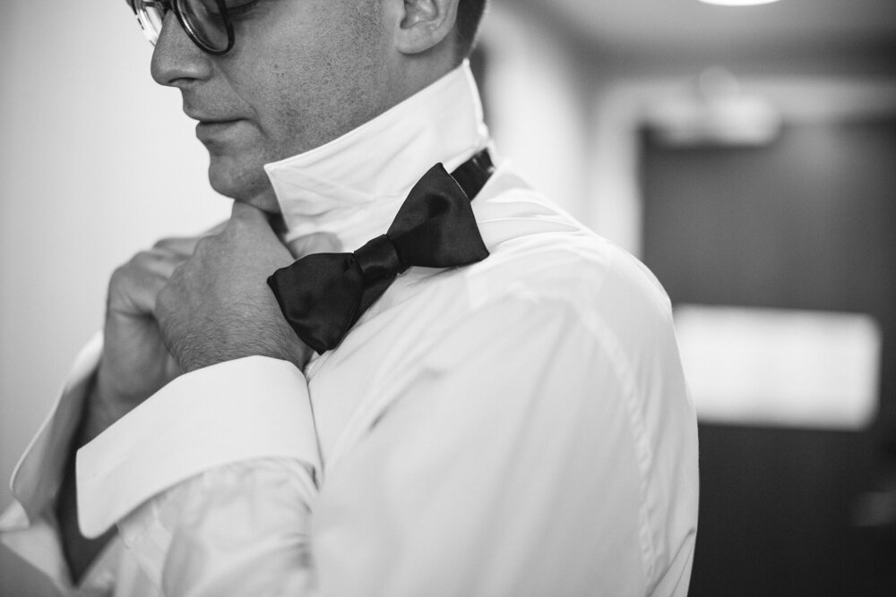 Groom adjusts his shirt collar. 

Luxury Local Wedding NYC. Wedding in Manhattan. New York City Wedding Photographer. Manhattan Luxury Wedding Photography. Museum of the City of New York Weddings.
