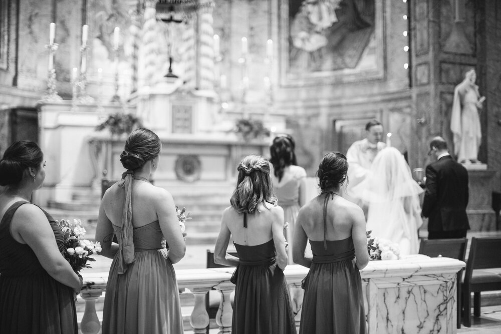 Bridesmaids stand in the foreground in focus, all in a line with bouquets in their hands, and facing away from the camera toward the altar where the bride and groom are standing out of focus.

Luxury Local Wedding NYC. Wedding in Manhattan. New York City Wedding Photographer. Manhattan Luxury Wedding Photography. Museum of the City of New York Weddings.