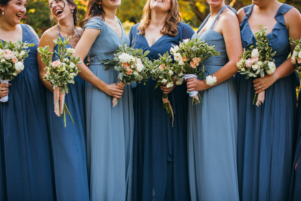 Bridesmaids are all standing next to each other in blue dresses with their bouquets of flowers in their hands. They are all smiling and looking at each other. They are photographed from the smile down.

Luxury Local Wedding NYC. Wedding in Manhattan. New York City Wedding Photographer. Manhattan Luxury Wedding Photography. Museum of the City of New York Weddings.