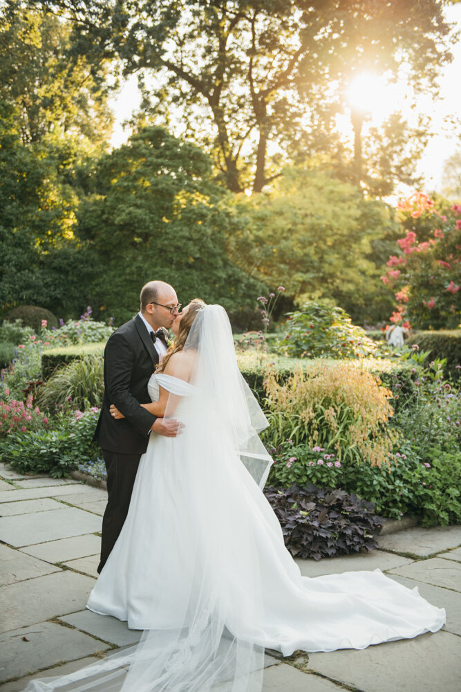 Bride and groom stand facing each other with arms around each other outside in the garden and kiss each other.

Luxury Local Wedding NYC. Wedding in Manhattan. New York City Wedding Photographer. Manhattan Luxury Wedding Photography. Museum of the City of New York Weddings.