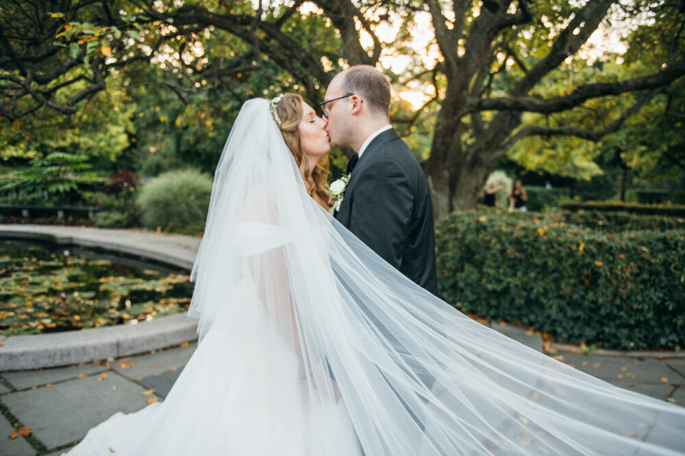 Bride and groom kiss outside in the garden. The bride's veil extends towards the camera.

Luxury Local Wedding NYC. Wedding in Manhattan. New York City Wedding Photographer. Manhattan Luxury Wedding Photography. Museum of the City of New York Weddings.