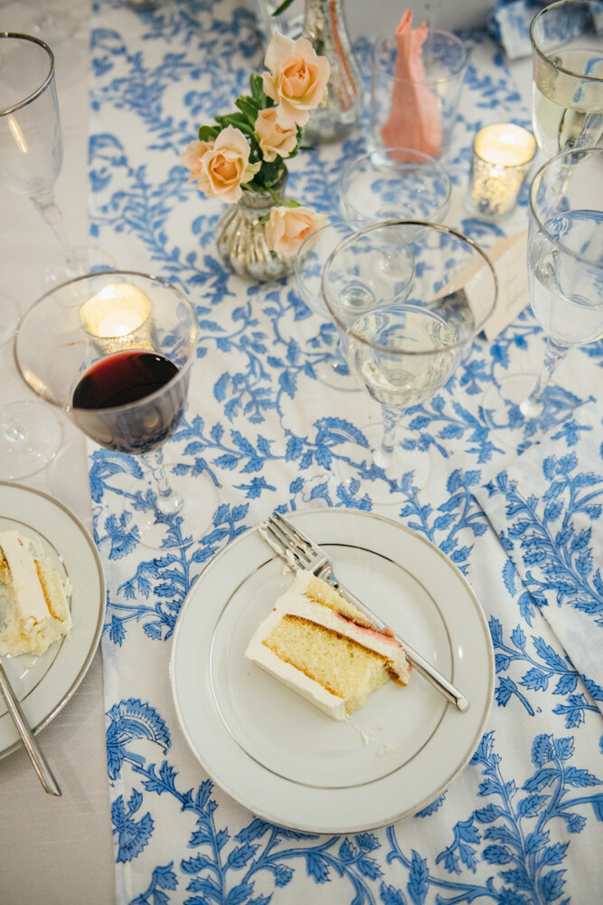 Detail shot of a slice of cut cake on a plate at a reception table with a blue and white table runner, flowers, and red-wine-filled glasses.

Luxury Local Wedding NYC. Wedding in Manhattan. New York City Wedding Photographer. Manhattan Luxury Wedding Photography. Museum of the City of New York Weddings.