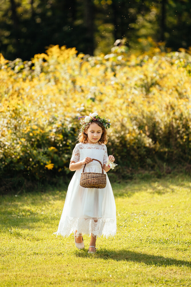 Flower girl approaches the outdoor wedding ceremony with a basket of flowers in her hand and a flower crown on her head.

Upstate New York Wedding Photographer. Upstate NY Wedding Photography. Luxury Local Wedding Upstate NY.