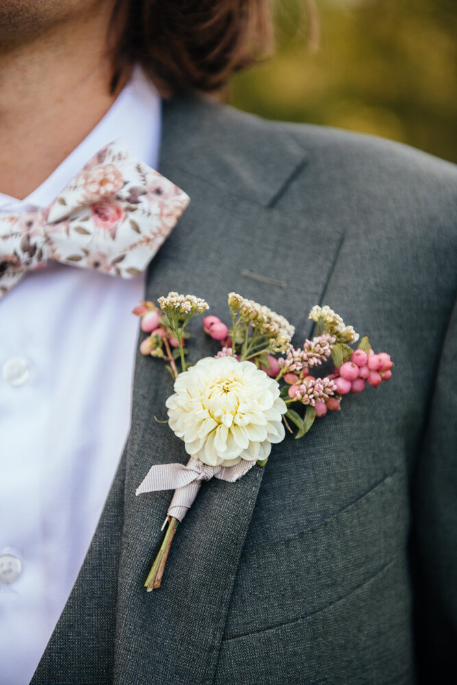 Close-up images of the groom's boutonnière, floral bowtie and grey suit.

Upstate New York Wedding Photographer. Upstate NY Wedding Photography. Luxury Local Wedding Upstate NY.