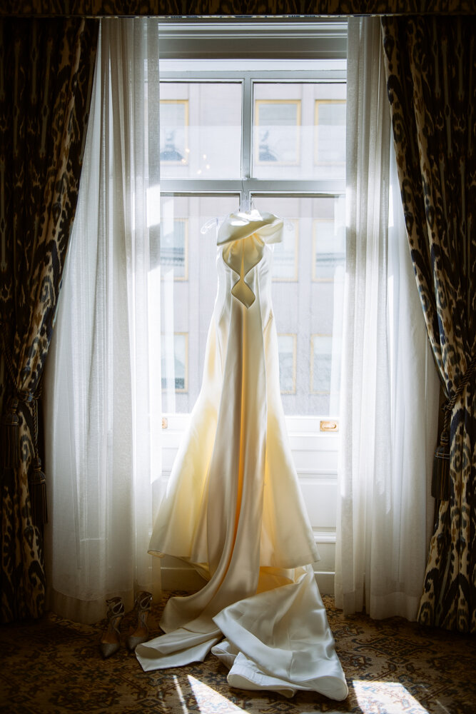 Wedding gown hangs from a tall window as the light shines into the room.

University Club Wedding Photographer. Manhattan Luxury Wedding Photographer. Manhattan Bridal Portraits. Luxury Local Wedding NYC. 