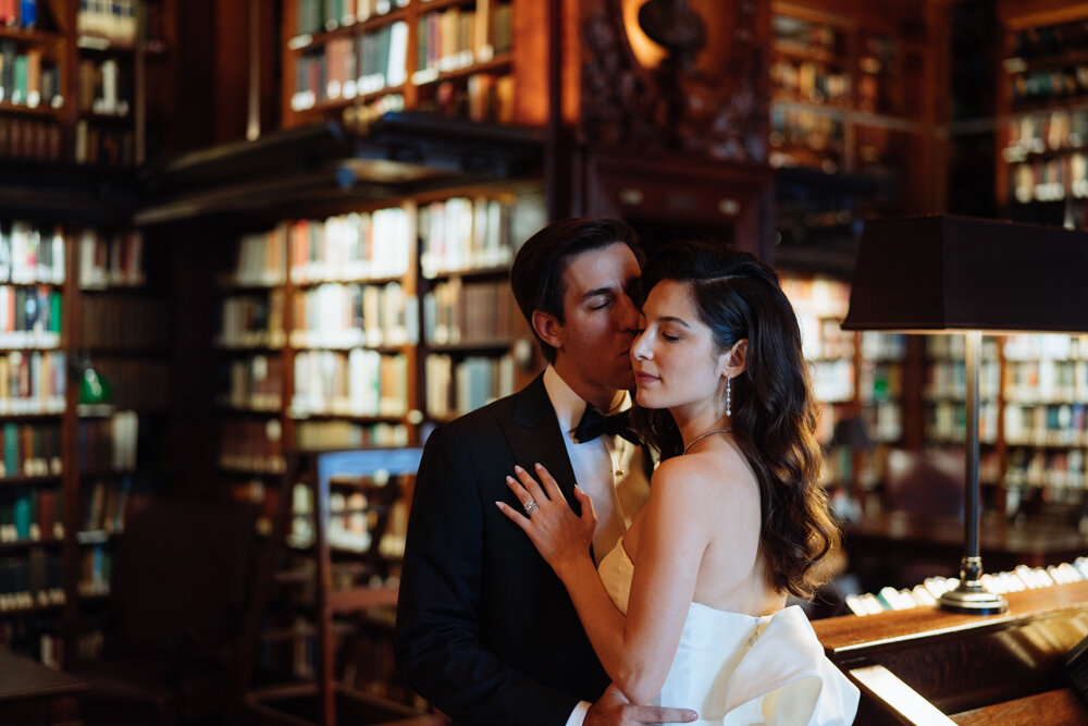Groom kisses the bride on the cheek. Her hand is on his chest. They both have their eyes closed. They are standing in the library of The University Club in New York City.

University Club Wedding Photographer. Manhattan Luxury Wedding Photographer. Manhattan Bridal Portraits. Luxury Local Wedding NYC. 
