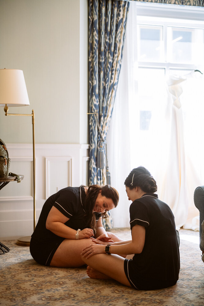 Two bridesmaids sitting on the floor in matching pajamas. One is painting the other's nails.

University Club Wedding Photographer. Manhattan Luxury Wedding Photographer. Manhattan Bridal Portraits. Luxury Local Wedding NYC. 