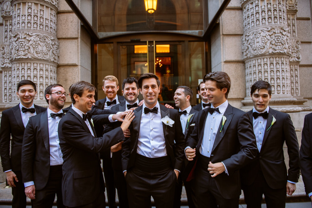 Groom stands with his hands in his pockets and smiles at the camera outside the University Club in New York City as his groomsmen touch his shoulder, look at him, or smile.

University Club Wedding Photographer. Manhattan Luxury Wedding Photographer. Manhattan Bridal Portraits. Luxury Local Wedding NYC. 