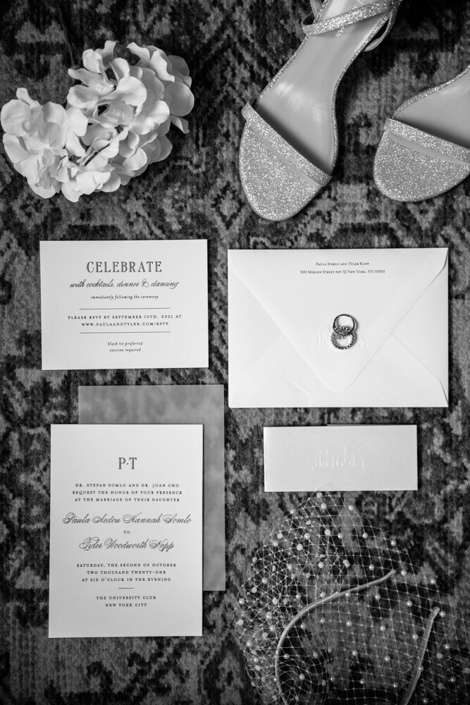 Detail photo of wedding invitations, bride's shoes, a veil headband, flowers, and wedding rings.

University Club Wedding Photographer. Manhattan Luxury Wedding Photographer. Manhattan Bride and Groom Portraits. Luxury Local Wedding NYC. 