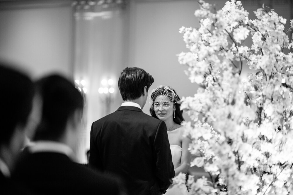 Photographed from behind the groom, the groom and the bride stand at the altar looking at each other.

University Club Wedding Photographer. Manhattan Luxury Wedding Photographer. Manhattan Bridal Portraits. Luxury Local Wedding NYC. 