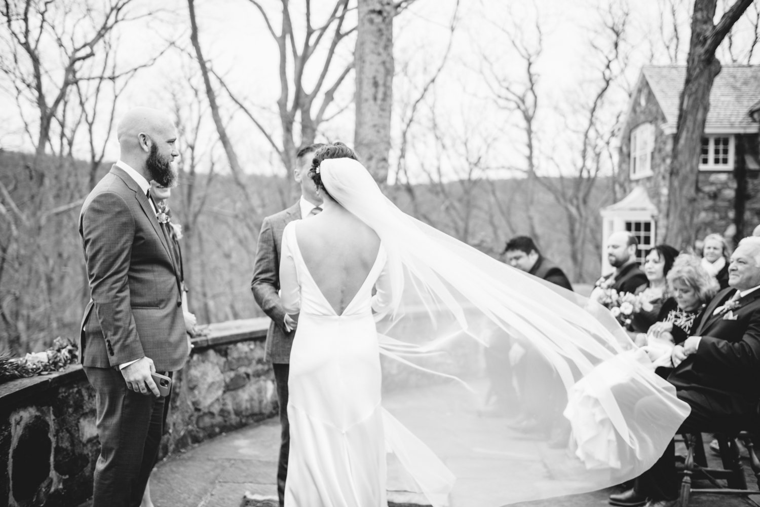 Bride faces toward the groom, away from the camera, as her veil blows in the wind.

Upstate New York Wedding Photography. Cold Spring NY Wedding Photography. Luxury Local Wedding Photographer. Destination Wedding Photographer.