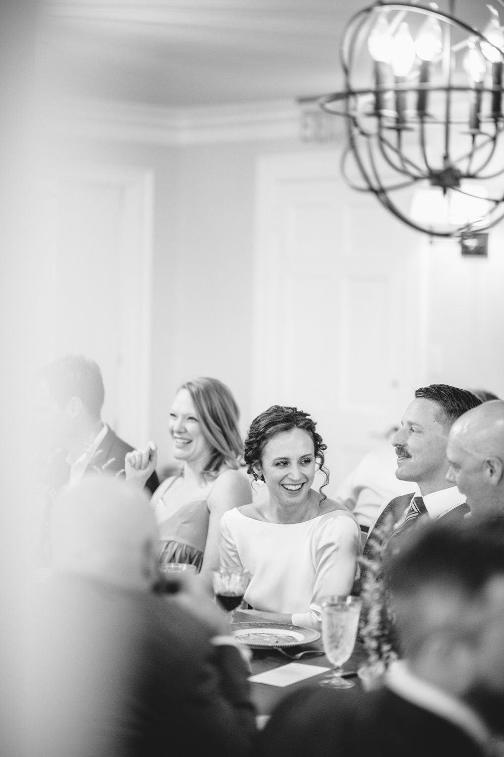 Bride smiles as she sits among wedding guests at the reception.

Upstate New York Wedding Photography. Cold Spring NY Wedding Photography. Luxury Local Wedding Photographer. Destination Wedding Photographer.