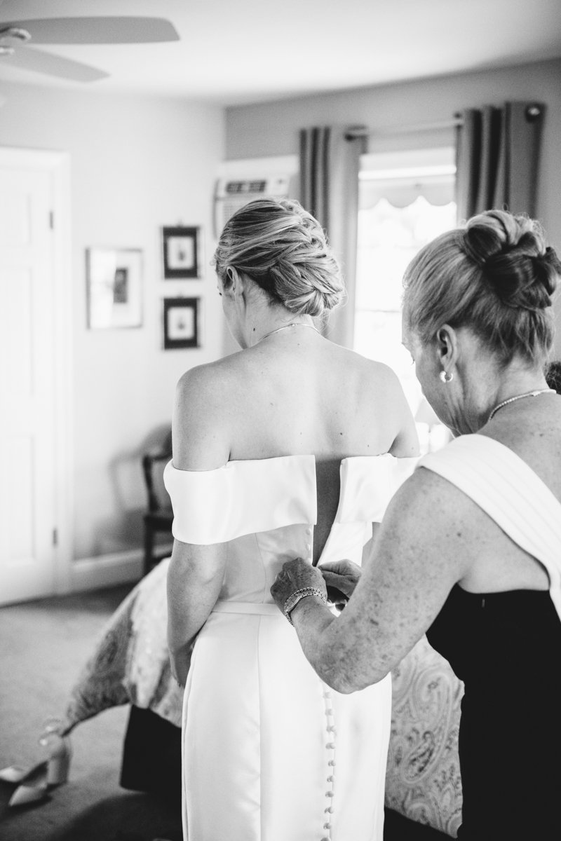 Bride's mother helps zip up her off the shoulder wedding dress.

New York Wedding Photography. Long Island Wedding Photography. Luxury Local Wedding Photographer. Destination Wedding Photographer.