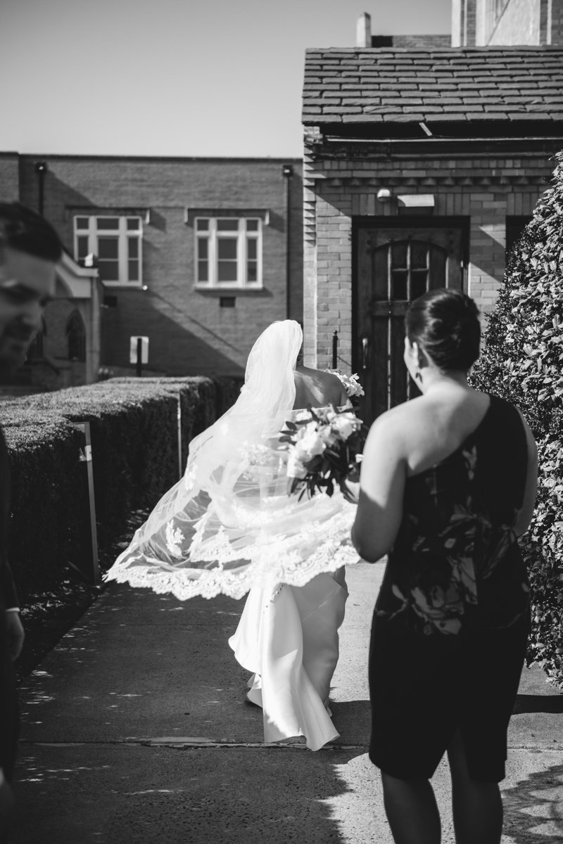 Bride walks outside toward a house with her veil blowing in the wind behind her. A bridesmaid follows behind her.

New York Wedding Photography. Long Island Wedding Photography. Luxury Local Wedding Photographer. Destination Wedding Photographer.