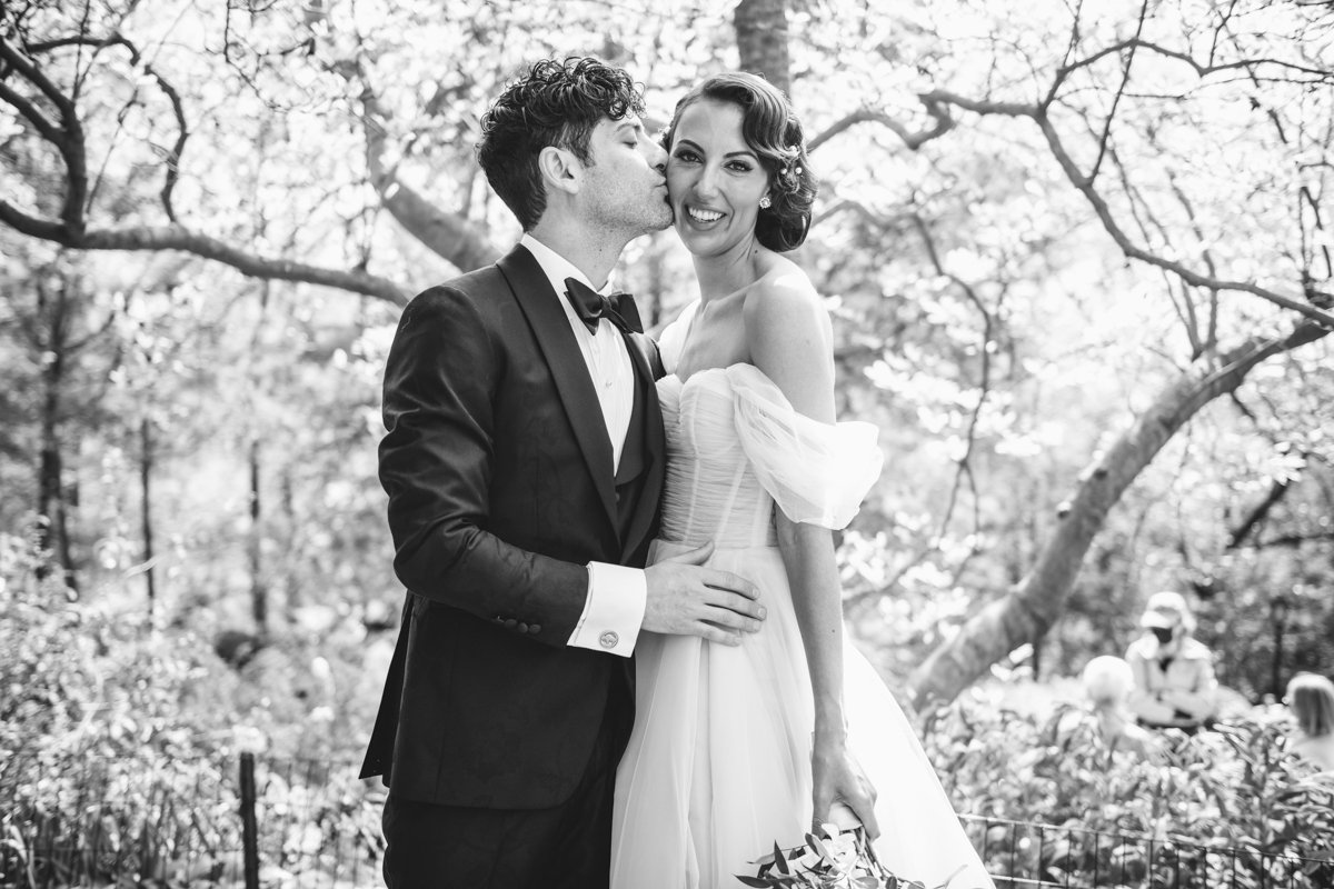 Bride and groom stand in front of trees. Groom kisses bride on the cheek as she smiles at the camera.

Manhattan Wedding Photographer. New York Wedding Photographer. New York Historical Society Wedding. NY Historical Society Weddings.