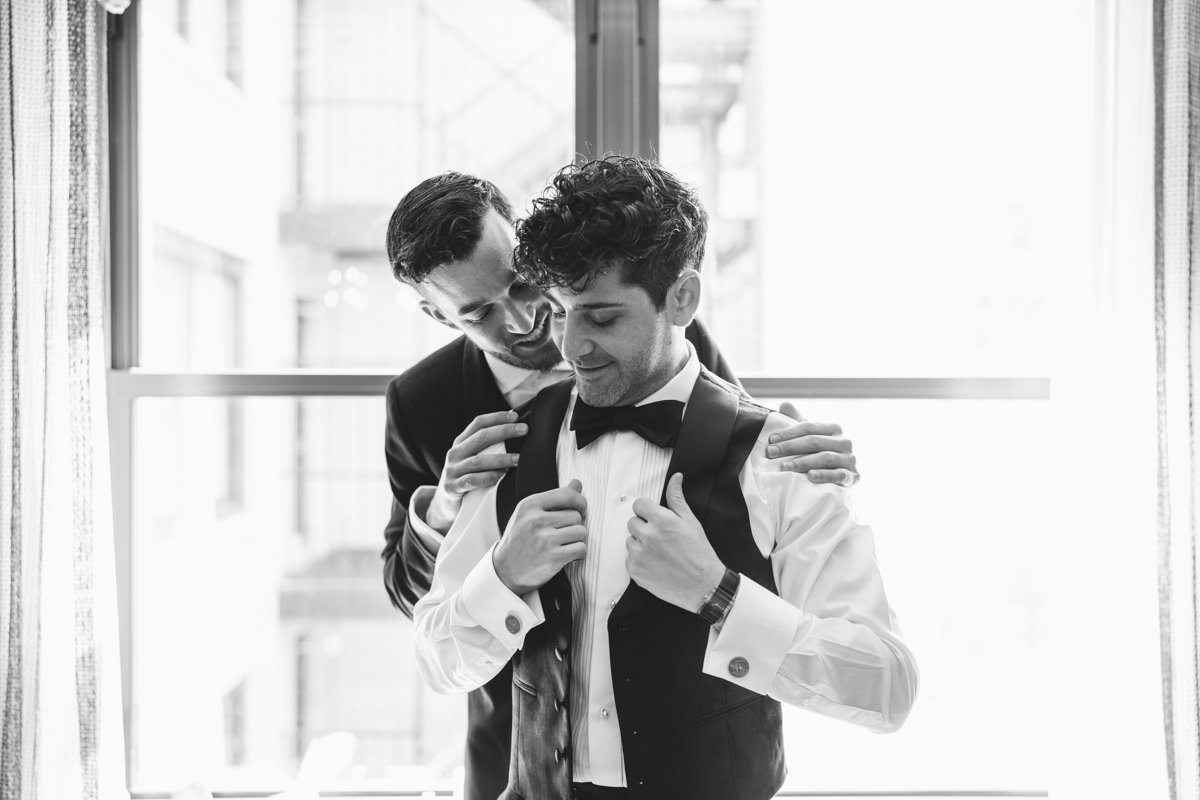 Groom stands in front of a window putting on his vest. A groomsman stands behind him with his hands on his shoulders.

Manhattan Wedding Photographer. New York Wedding Photographer. New York Historical Society Wedding. NY Historical Society Weddings.