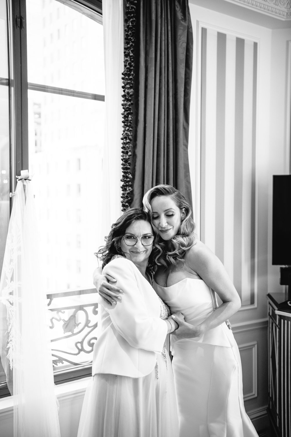 Bride is wearing her wedding gown and hugging her mother. Both are smiling. 

Manhattan Luxury Wedding. New York Luxury Wedding Photographer. Wedding in Manhattan. NYC Luxury Wedding.