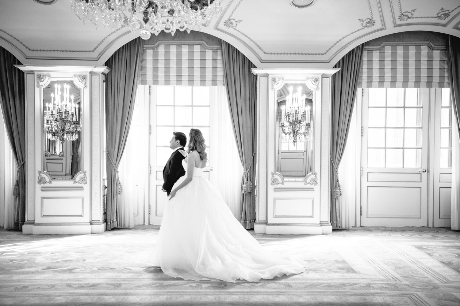In the St. Regis in Manhattan, the groom is standing facing the end of the room and the bride taps his shoulder from behind him.

Manhattan Luxury Wedding. New York Luxury Wedding Photographer. Wedding in Manhattan. NYC Luxury Wedding.