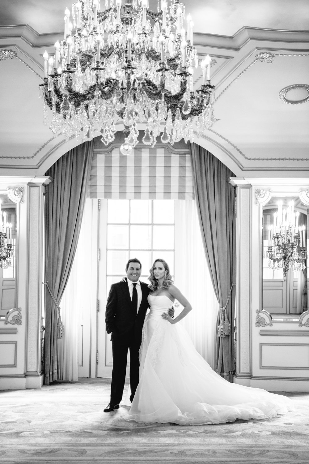 Bride and groom stand below a grand chandelier in the St. Regis in Manhattan. They have an arm around each other and are both smiling at the camera.

Manhattan Luxury Wedding. New York Luxury Wedding Photographer. Wedding in Manhattan. NYC Luxury Wedding.
