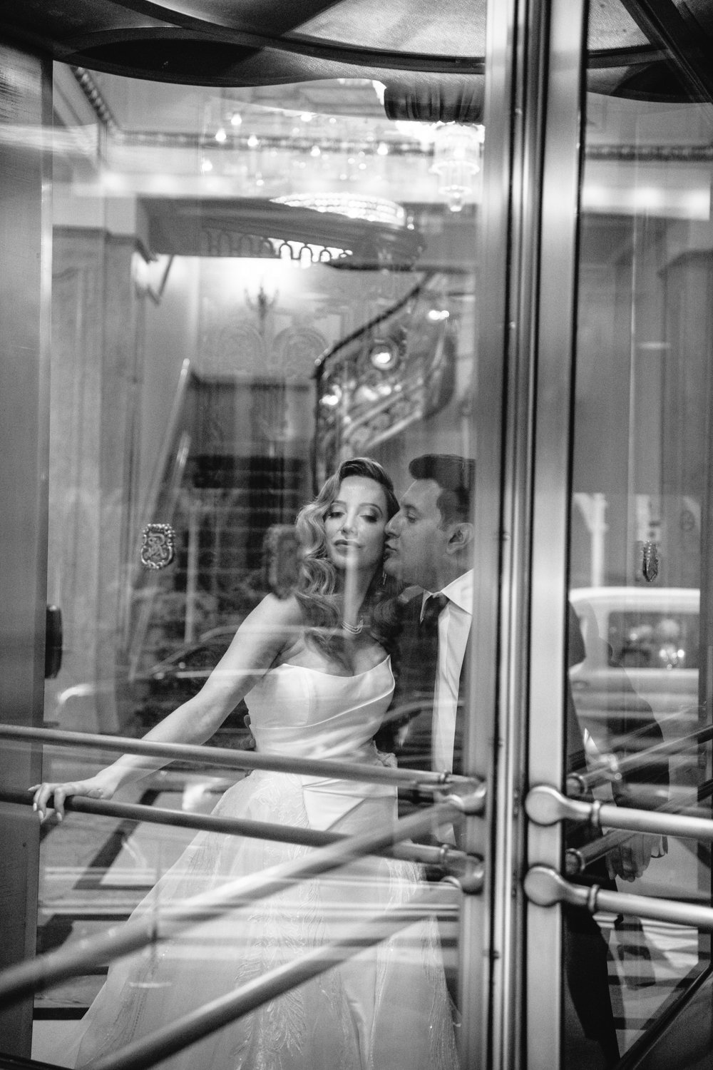 Groom kisses bride on cheek as they stand on the inside of a glass door. They are photographed from outside the building.

Manhattan Luxury Wedding. New York Luxury Wedding Photographer. Wedding in Manhattan. NYC Luxury Wedding.