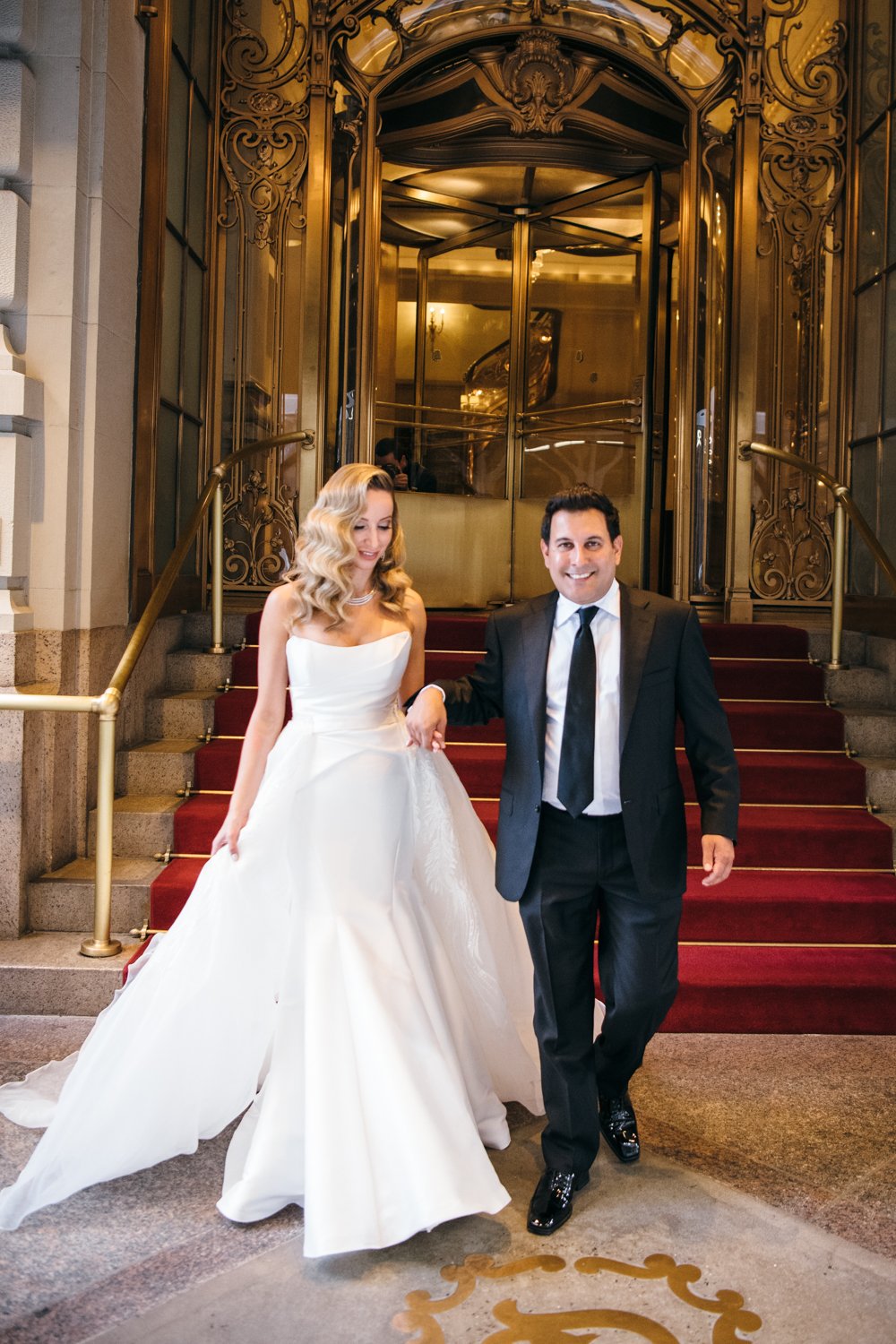 Bride and groom walk down the steps of the St. Regis in Manhattan as they hold hands.

Manhattan Luxury Wedding. New York Luxury Wedding Photographer. Wedding in Manhattan. NYC Luxury Wedding.