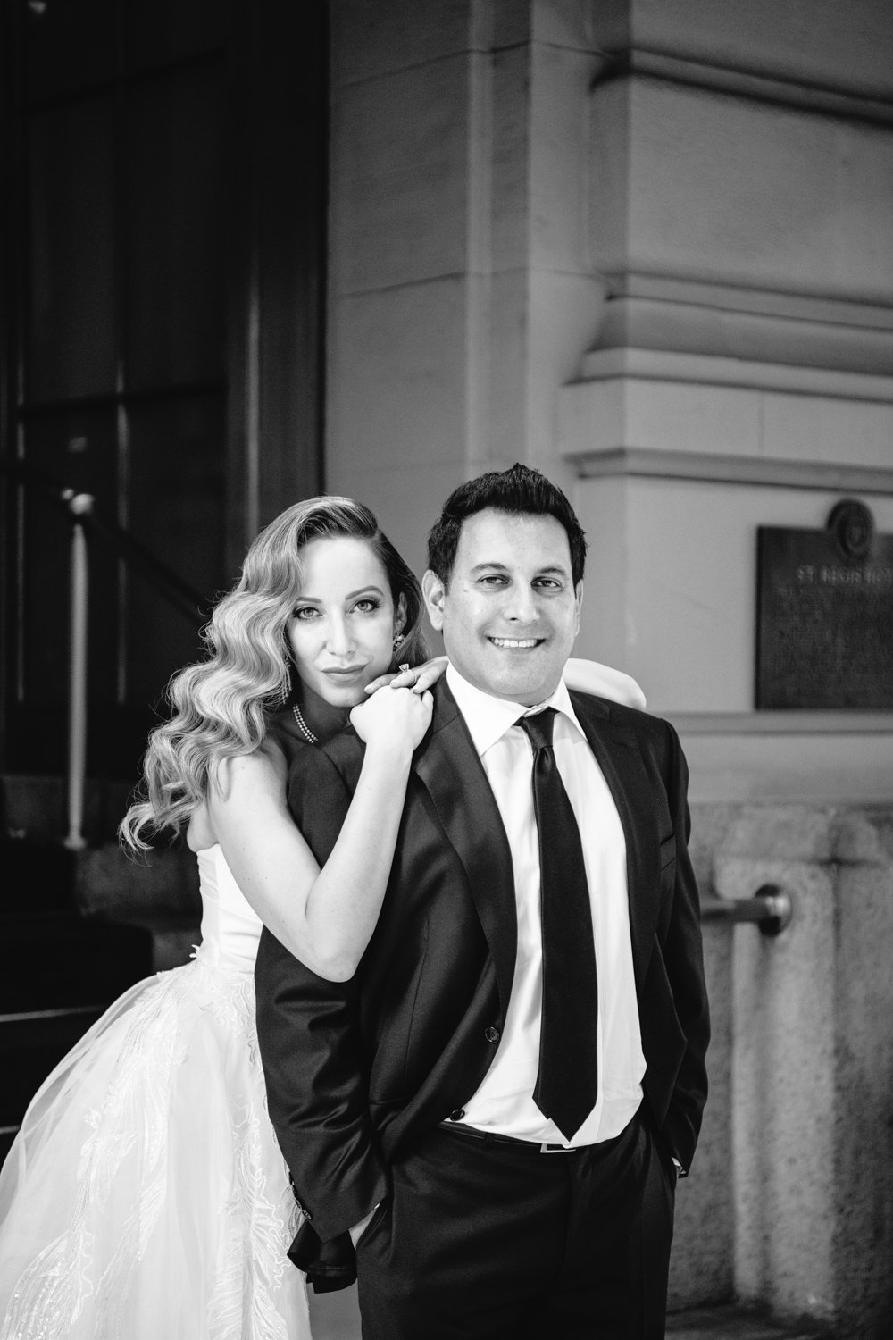 Bride and groom stand outside the St. Regis in Manhattan. The bride is standing behind the groom with her arms leaning on his shoulders.

Manhattan Luxury Wedding. New York Luxury Wedding Photographer. Wedding in Manhattan. NYC Luxury Wedding. Manhattan Bridal Portraits.