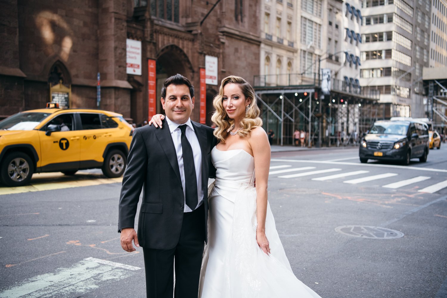 Bride and groom stand on a Manhattan street with arms around each other, both looking at the camera and smiling. Cars and taxis are driving along the street behind them.

Manhattan Luxury Wedding. New York Luxury Wedding Photographer. Wedding in Manhattan. NYC Luxury Wedding. Manhattan Bridal Portraits.