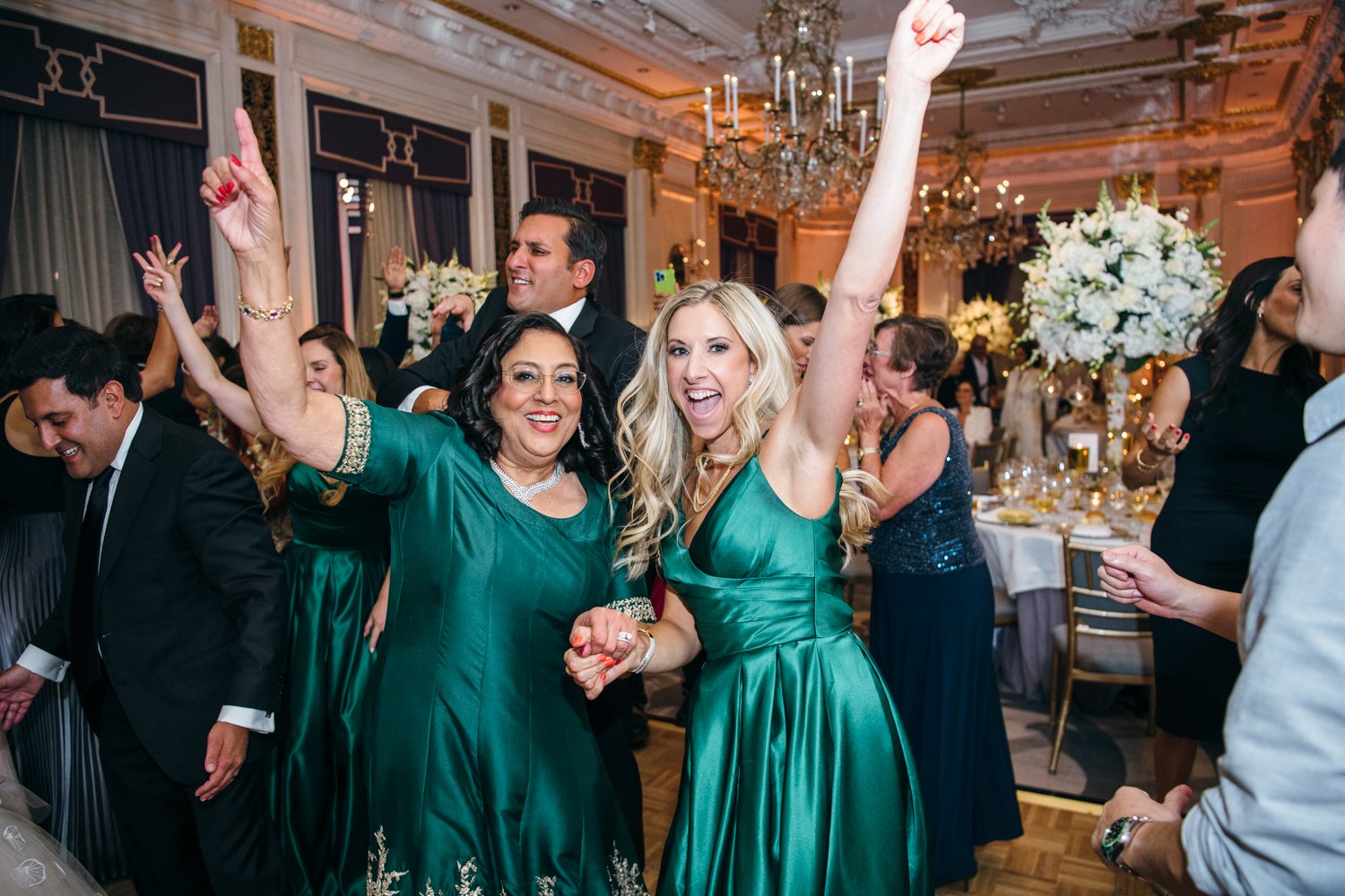Bridesmaid and wedding guest in green dresses have their hands in the air with big smiles on their faces. The St. Regis ballroom is full of wedding guests behind them.

Manhattan Luxury Wedding. New York Luxury Wedding Photographer. Wedding in Manhattan. NYC Luxury Wedding.