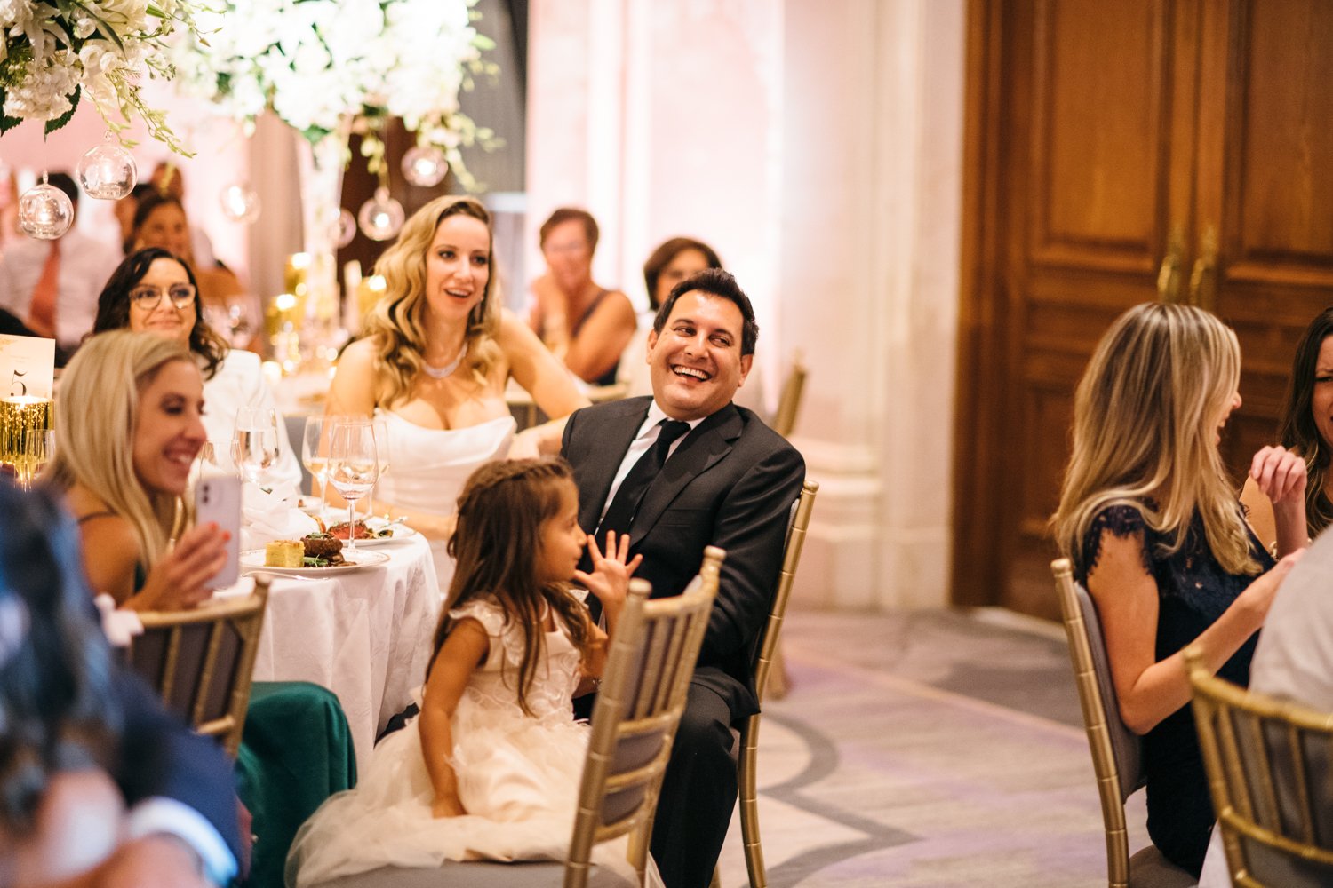 Bride and groom are seated beside their wedding guests and smile and laugh.

Manhattan Luxury Wedding. New York Luxury Wedding Photographer. Wedding in Manhattan. NYC Luxury Wedding.